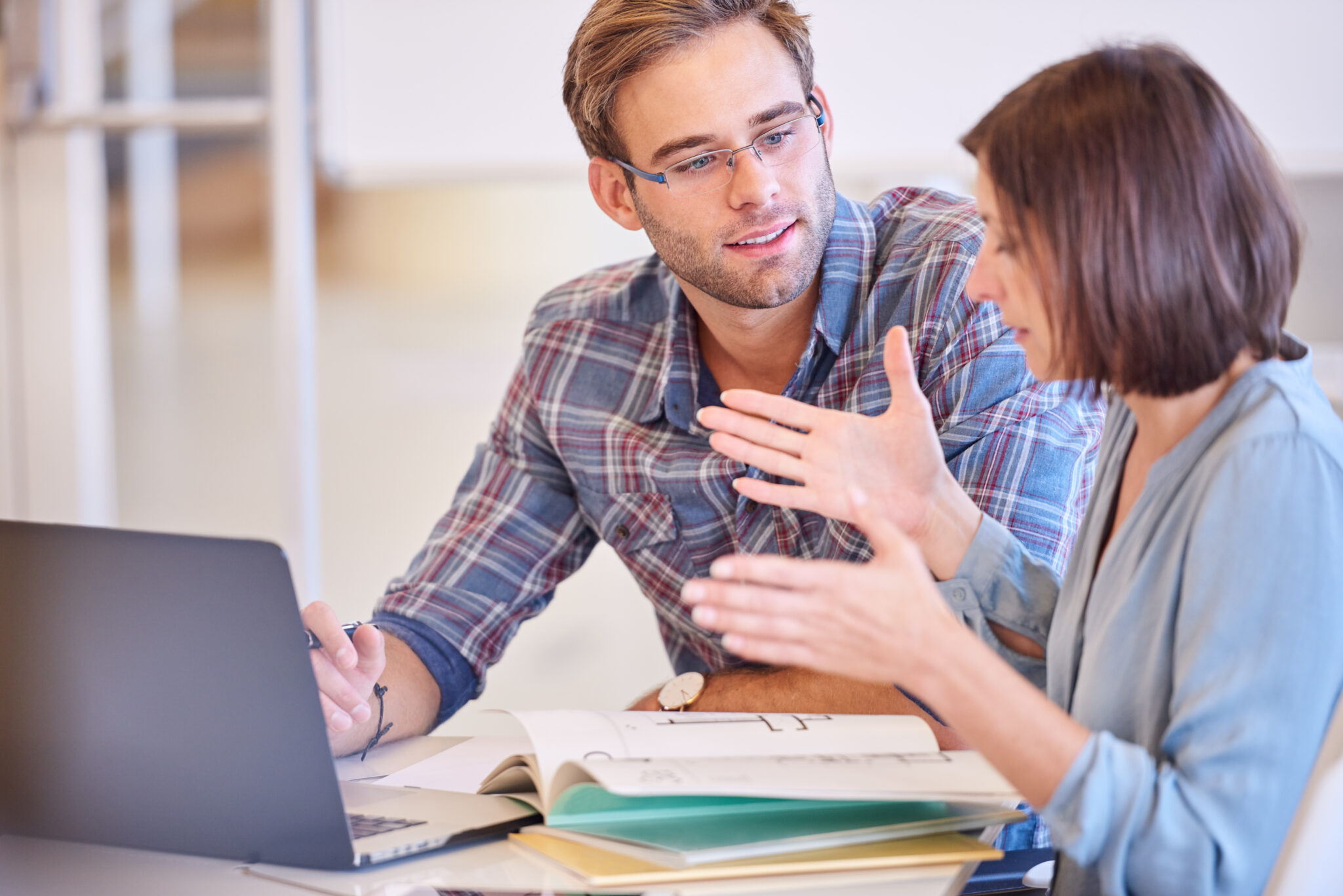 Adult man with trimmed beard looking at his female partner as she explains the specifics of their business plan and future partnership.