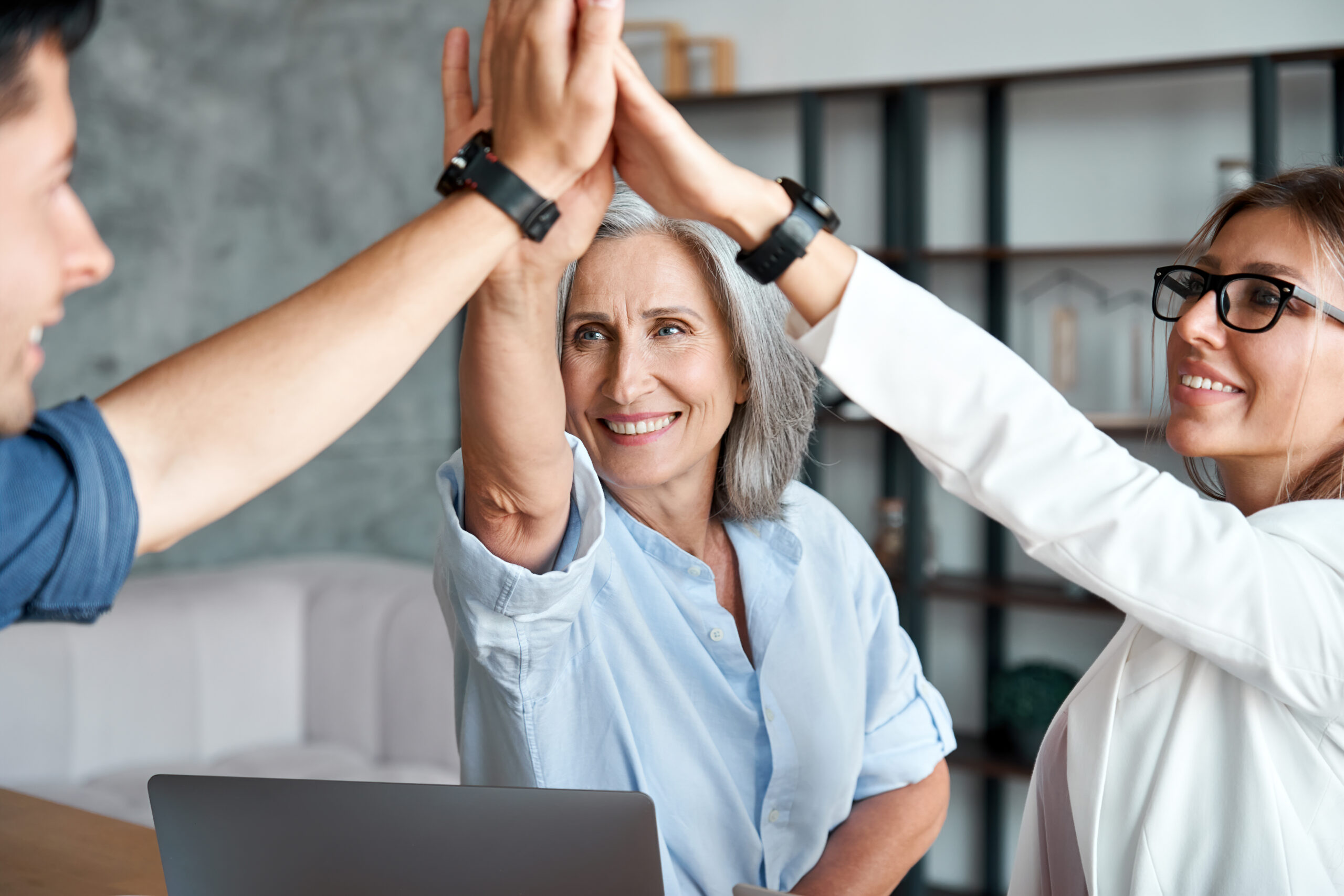 Happy mature old female mentor teacher executive giving high five to young enthusiastic employees, interns, students united team as teamwork support, professional leadership and partnership concept.